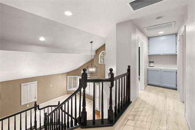 hallway featuring a notable chandelier, vaulted ceiling, and light hardwood / wood-style floors