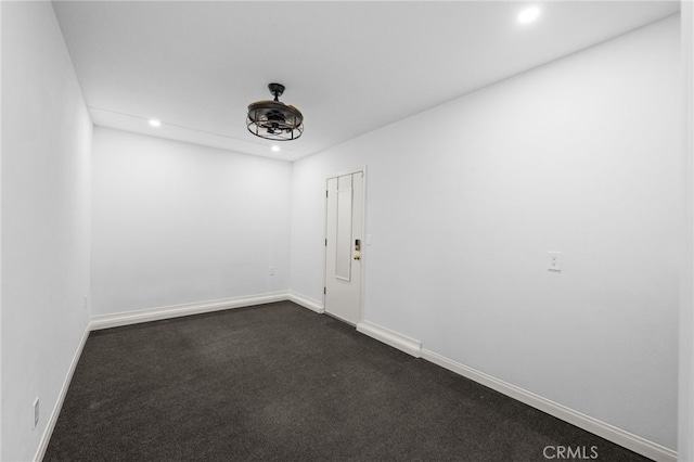 spare room with dark colored carpet