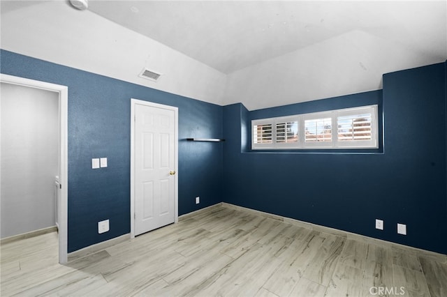 unfurnished bedroom with lofted ceiling and light hardwood / wood-style floors