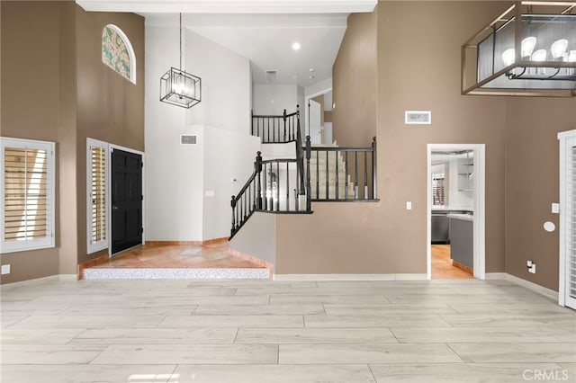 foyer featuring light wood-type flooring, an inviting chandelier, and a towering ceiling