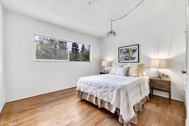 bedroom with hardwood / wood-style floors and a textured ceiling