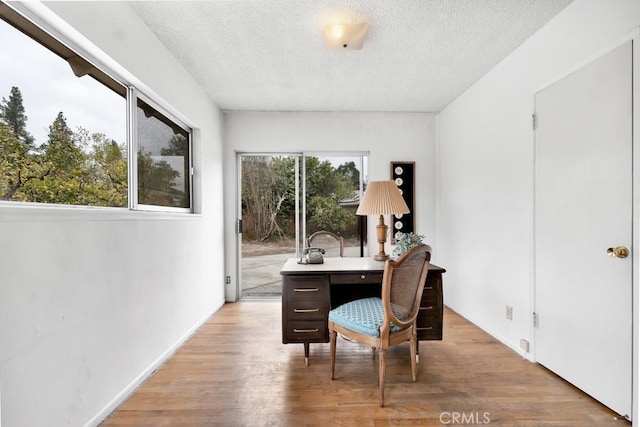 home office with light hardwood / wood-style flooring and a textured ceiling