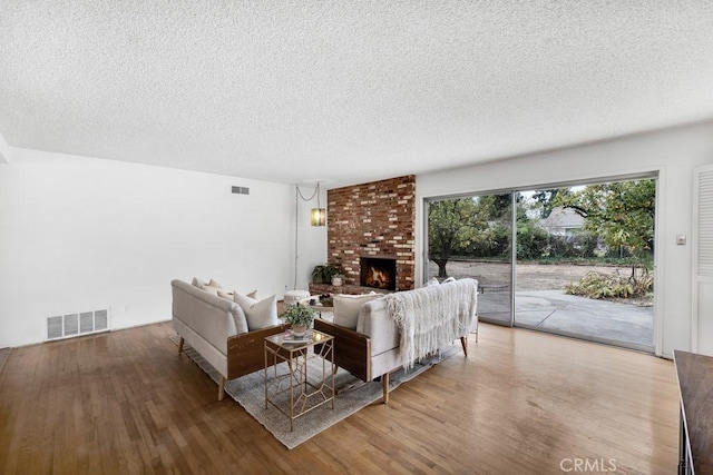 living room featuring wood-type flooring, a fireplace, and a textured ceiling