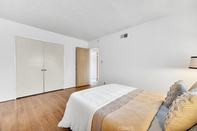 bedroom with hardwood / wood-style flooring, a textured ceiling, and a closet