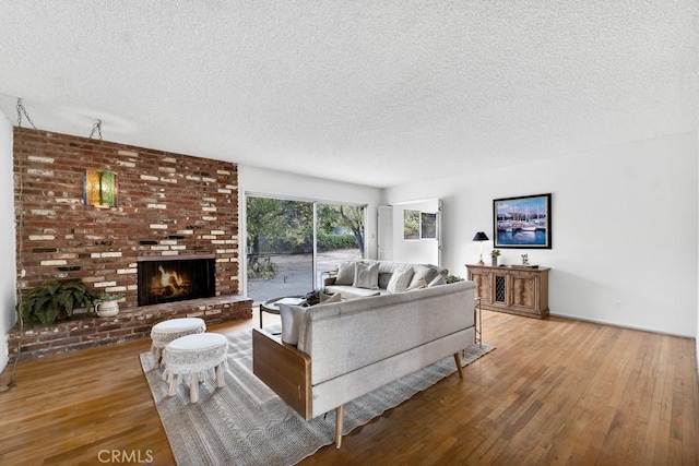 living room featuring a fireplace, wood-type flooring, and a textured ceiling