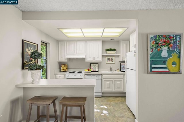 kitchen with white cabinetry, white appliances, a breakfast bar, and sink