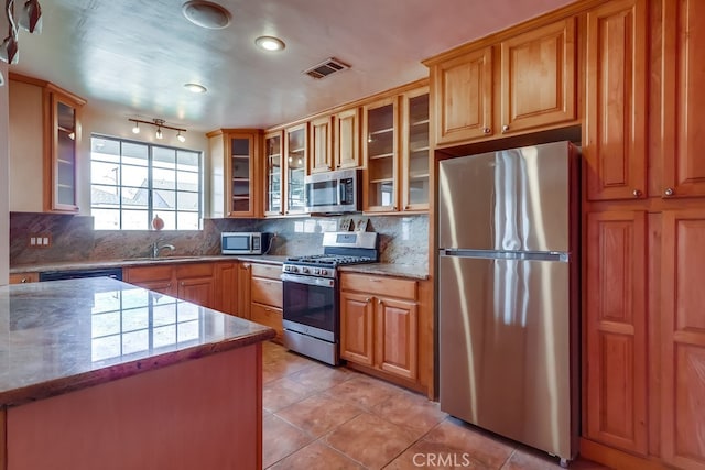 kitchen featuring light tile patterned flooring, stainless steel appliances, sink, and tasteful backsplash