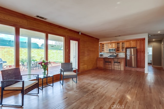 kitchen with a breakfast bar area, stainless steel appliances, kitchen peninsula, and light wood-type flooring