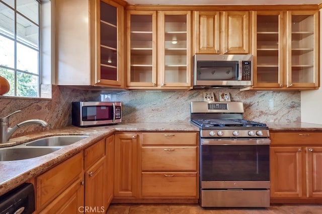 kitchen with sink, stainless steel appliances, light stone countertops, light tile patterned flooring, and decorative backsplash