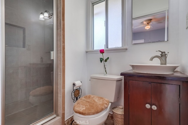 bathroom with a shower with door, vanity, ceiling fan, and toilet