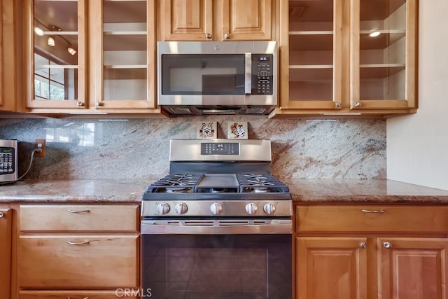 kitchen with light stone counters, decorative backsplash, and stainless steel appliances