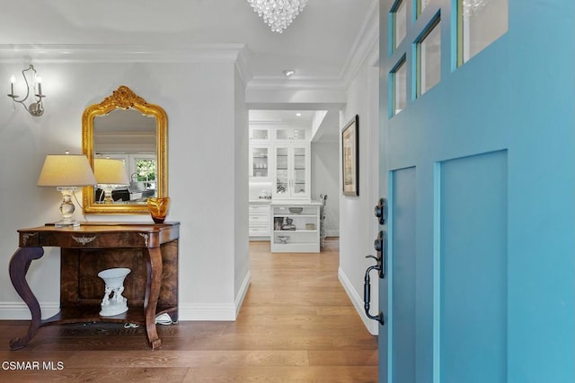 entrance foyer with crown molding, a chandelier, and hardwood / wood-style flooring