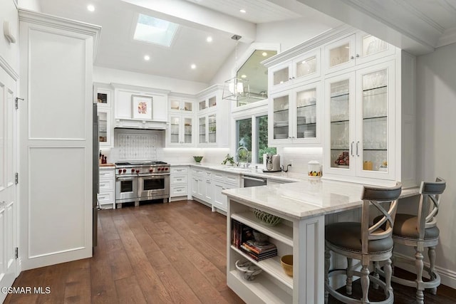 kitchen featuring appliances with stainless steel finishes, a breakfast bar, white cabinets, light stone counters, and kitchen peninsula