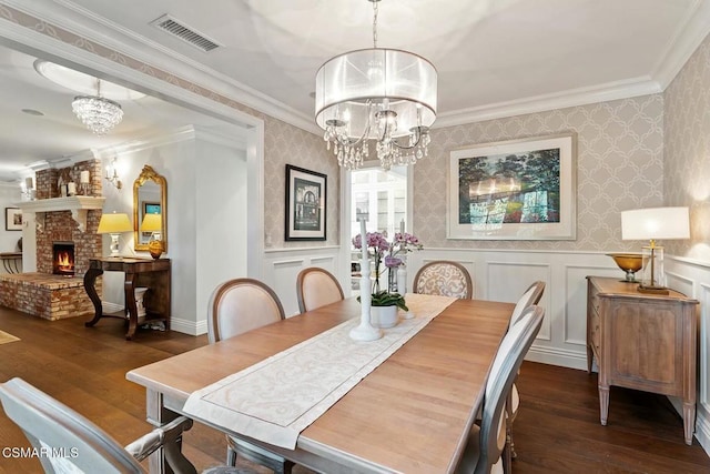 dining space featuring an inviting chandelier, a brick fireplace, and dark hardwood / wood-style floors