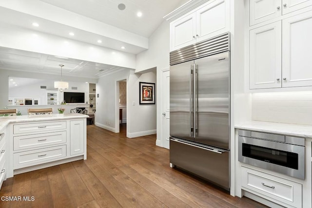 kitchen with white cabinetry, tasteful backsplash, built in appliances, light hardwood / wood-style flooring, and pendant lighting