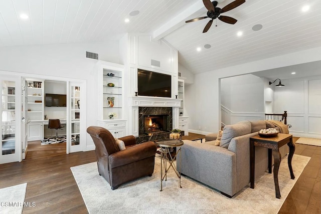 living room featuring vaulted ceiling with beams, hardwood / wood-style floors, a high end fireplace, and french doors