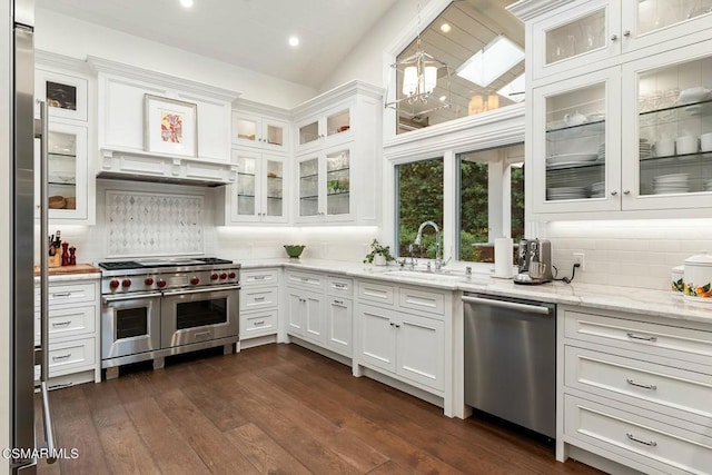 kitchen featuring appliances with stainless steel finishes, dark hardwood / wood-style floors, light stone countertops, white cabinets, and vaulted ceiling