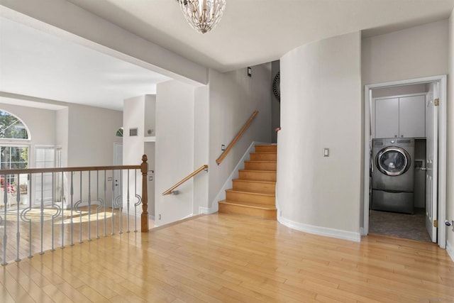 staircase featuring washer / dryer, a chandelier, and hardwood / wood-style flooring