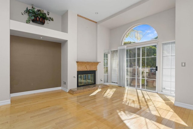 unfurnished living room with hardwood / wood-style flooring and a towering ceiling