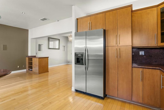 kitchen featuring light hardwood / wood-style floors, stainless steel fridge with ice dispenser, and backsplash