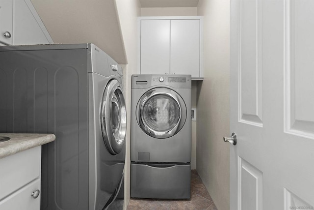 washroom featuring cabinets, independent washer and dryer, and dark tile patterned flooring