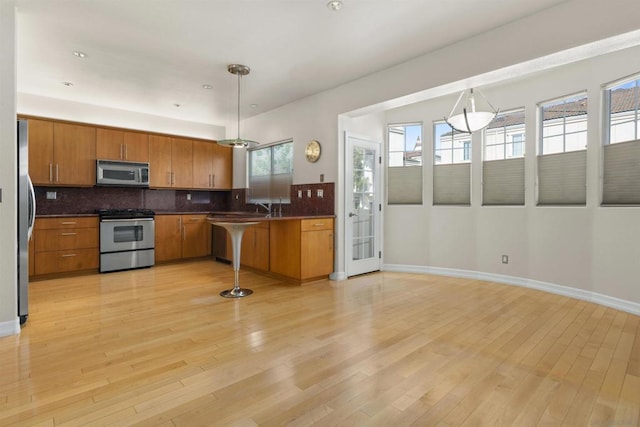 kitchen with stainless steel appliances, pendant lighting, backsplash, and kitchen peninsula