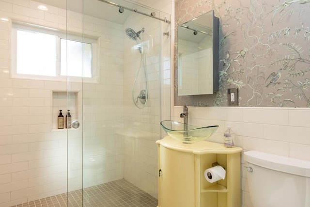 bathroom with vanity, a shower with shower door, tile walls, and toilet