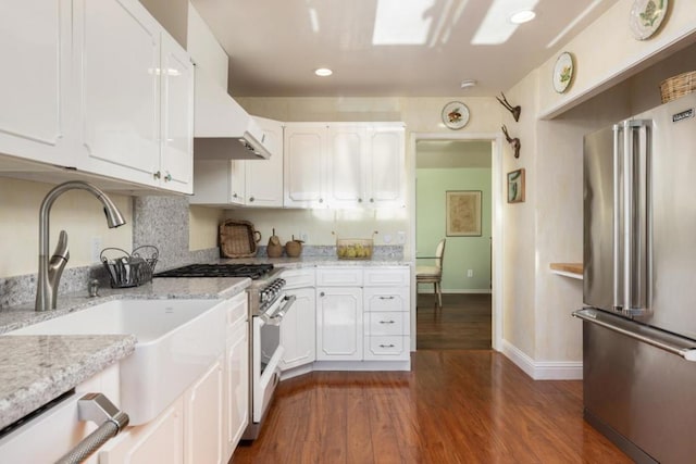 kitchen with high end appliances, dark hardwood / wood-style floors, light stone countertops, and white cabinets