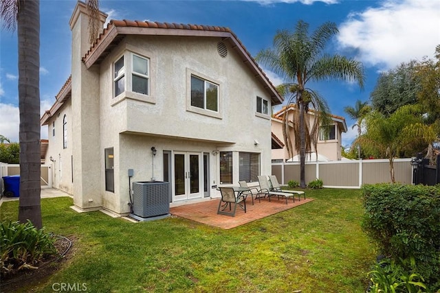 back of property with french doors, a patio, central AC, and a lawn