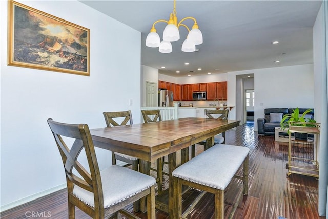 dining area featuring sink, an inviting chandelier, and dark hardwood / wood-style flooring