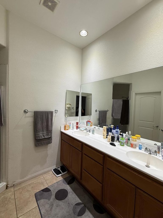 bathroom with tile patterned flooring, vanity, and walk in shower