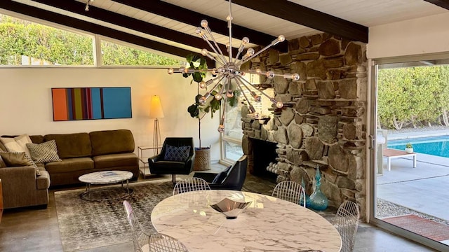 interior space featuring lofted ceiling with beams, a stone fireplace, and a chandelier