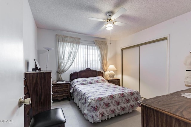 carpeted bedroom featuring ceiling fan, a closet, and a textured ceiling