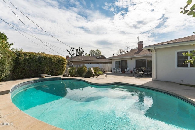 view of swimming pool with a diving board and a patio