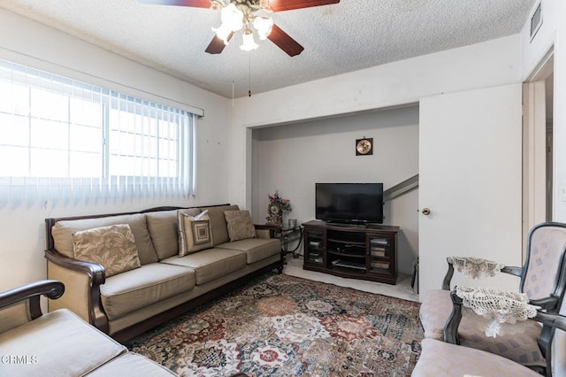 carpeted living room featuring ceiling fan and a textured ceiling