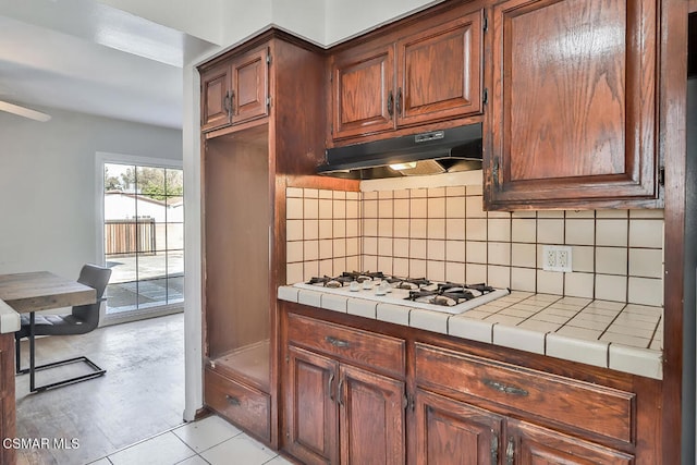 kitchen with white gas stovetop, tile counters, and decorative backsplash