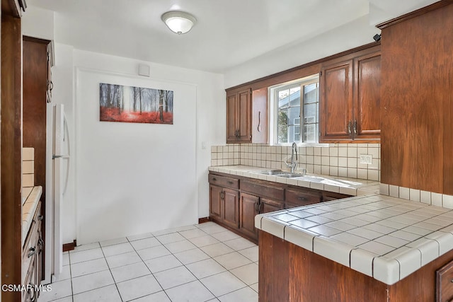 kitchen featuring light tile patterned flooring, sink, decorative backsplash, tile counters, and kitchen peninsula