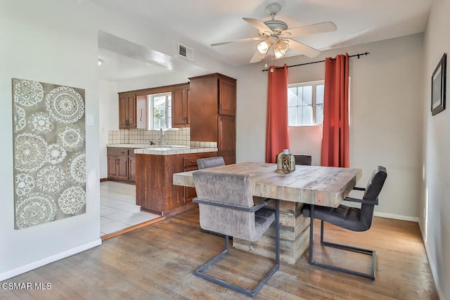 dining room featuring ceiling fan, sink, and light wood-type flooring