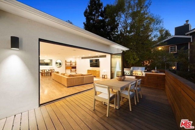 wooden terrace with an outdoor living space, an outdoor kitchen, and area for grilling