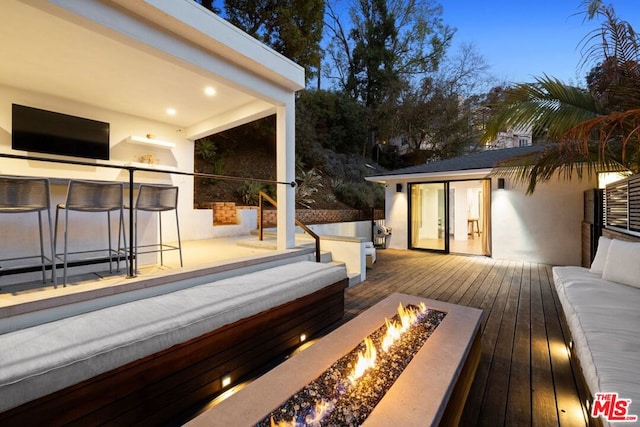 wooden terrace featuring an outdoor living space with a fire pit