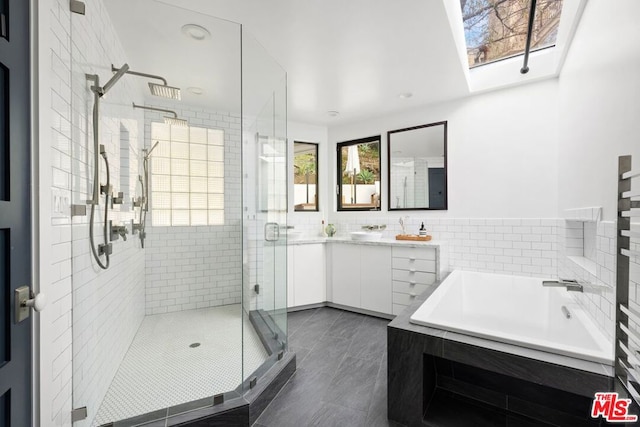 bathroom featuring vanity, independent shower and bath, and tile walls