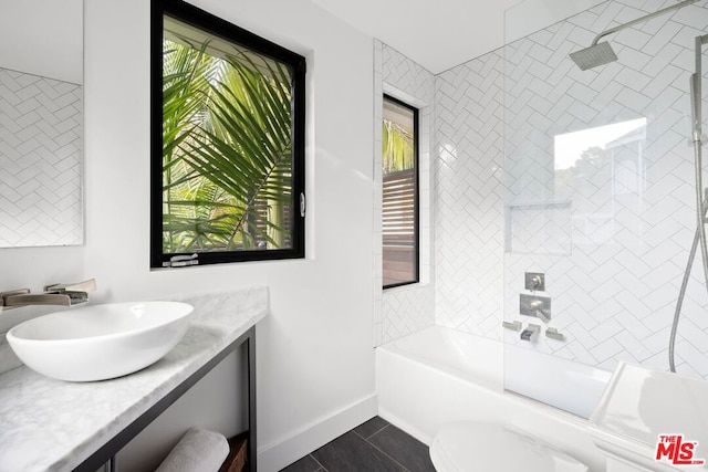 full bathroom with tiled shower / bath, vanity, toilet, and tile patterned floors