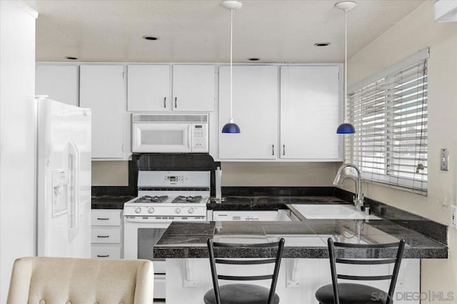 kitchen with white appliances, a breakfast bar, and white cabinets