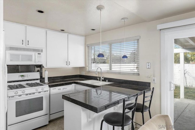 kitchen with decorative light fixtures, white appliances, a kitchen breakfast bar, and white cabinets