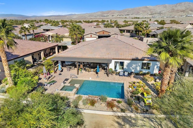 exterior space with an in ground hot tub, a mountain view, and a patio area