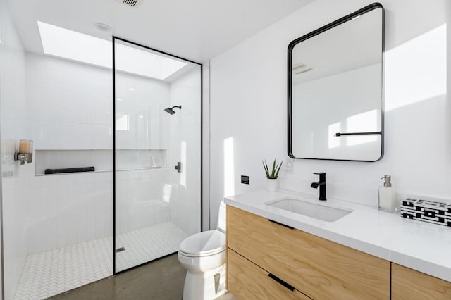 bathroom with vanity, tiled shower, and toilet