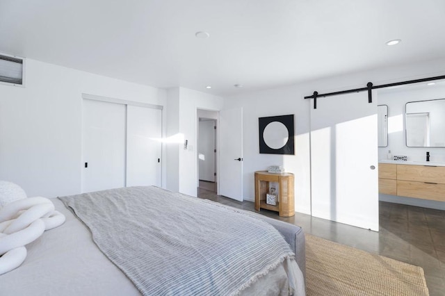 bedroom with a closet, a barn door, and ensuite bathroom