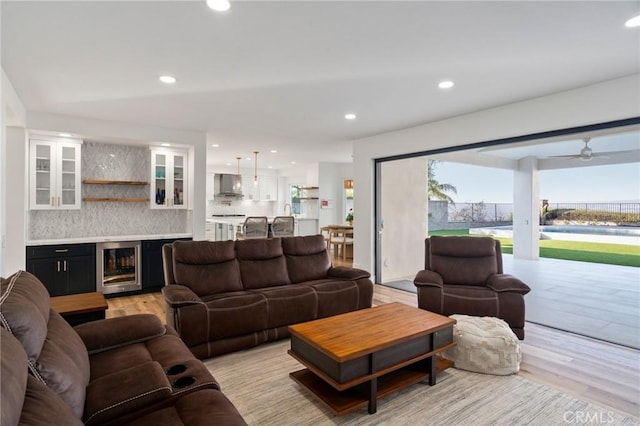 living room with wine cooler, indoor bar, and light wood-type flooring