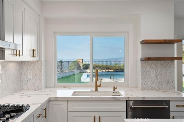 kitchen featuring light stone counters, sink, and white cabinets