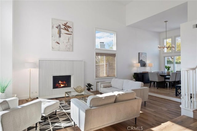 living room with a towering ceiling, a chandelier, and hardwood / wood-style flooring